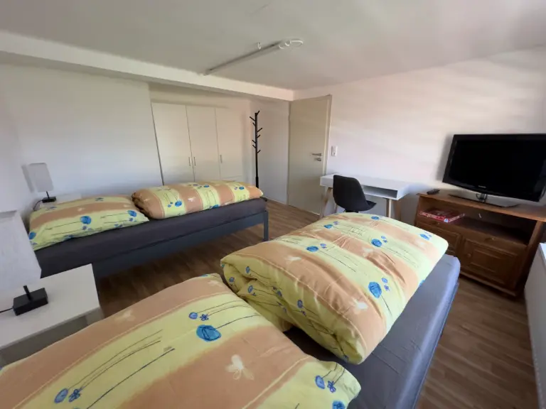 Helles Doppelbettzimmer im Obergeschoss mit Schreibtisch und Fernseher, ideal für Monteure in Jena