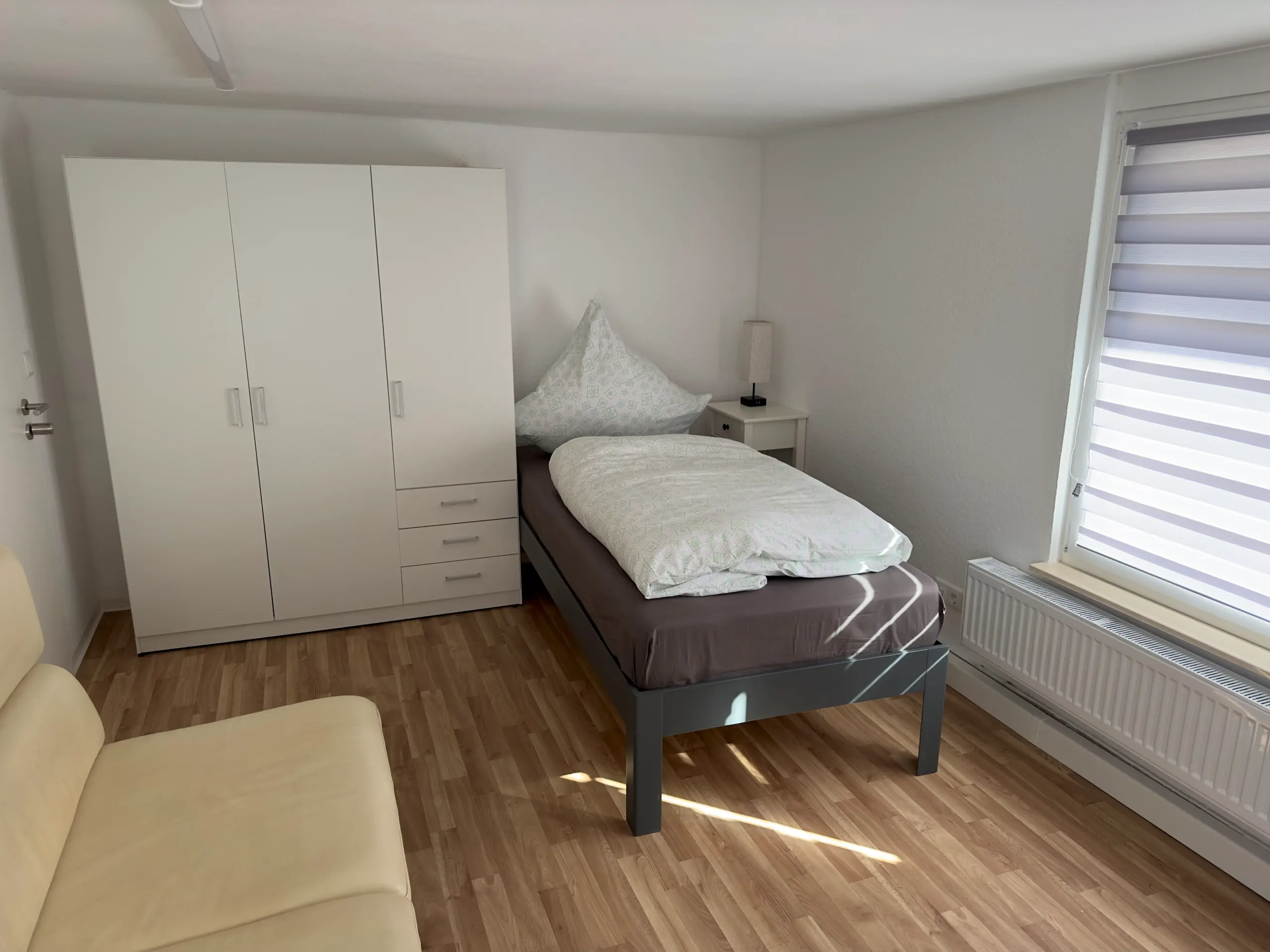 Helles Doppelbettzimmer im Obergeschoss mit Sofa, Einzelbett und Kleiderschrank, ideal für Monteure in Jena