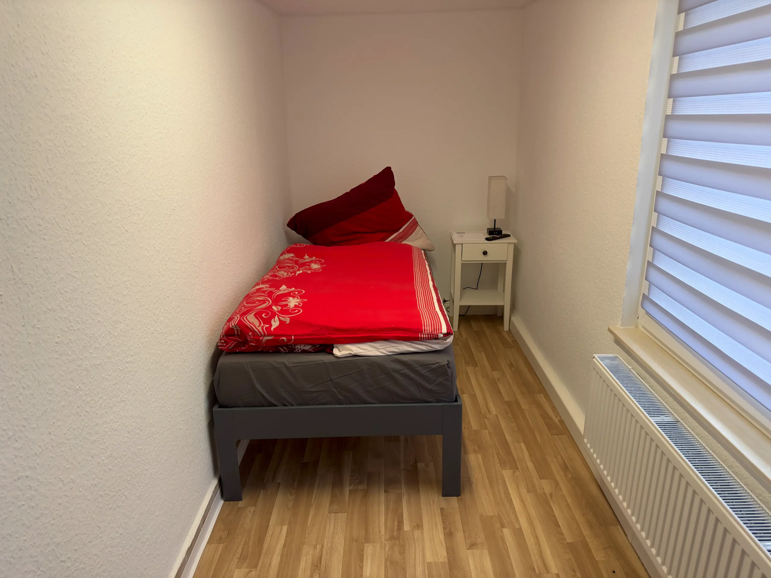 Gemütliches Einzelbettzimmer im Obergeschoss mit großem Fenster und Nachttisch, ideal für Monteure in Jena